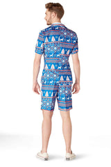 A person stands facing away, dressed in the Christmas Blue Nordic short-sleeve shirt and shorts from Suitmeister, showcasing a holiday-themed pattern with snowflakes and reindeer motifs. They are also wearing white slip-on shoes.