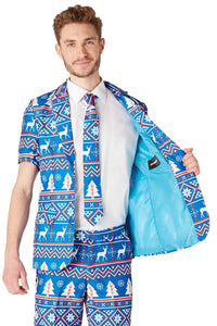 A man is dressed in the Suitmeister Christmas Blue Nordic suit, adorned with festive reindeer and snowflake patterns. He is showing off the light blue lining of his jacket and wearing a matching tie, all set against a white backdrop.