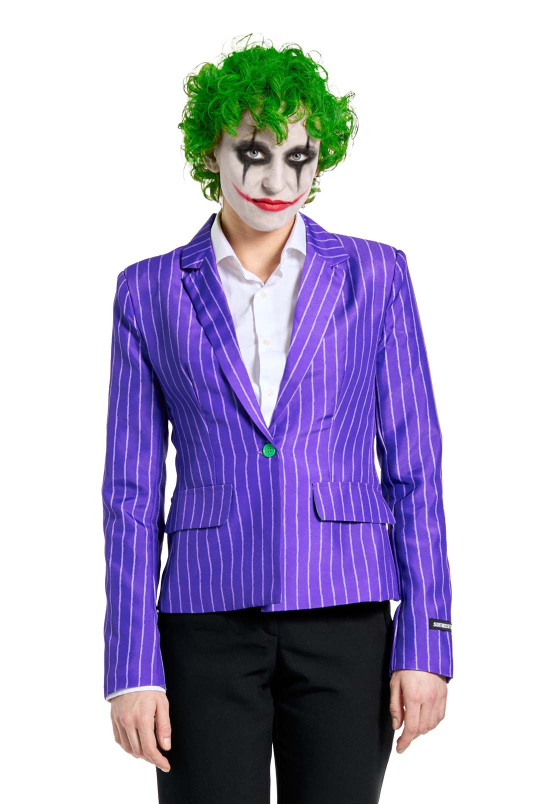 A person dressed in an ensemble featuring "The Joker Jacket" by Suitmeister, adorned with a bright green wig, white face paint with dramatic black eye makeup, a red painted smile, a purple pinstripe blazer, and black pants, posed against a white background.