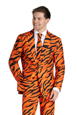 A man with a smile, dressed in a Suitmeister Tiger suit in vibrant orange and black tiger stripes, paired with a matching tie and white dress shirt, has his hand in his pocket. He sports short brown hair and is looking to the side.