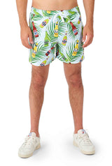 A person is dressed in Suitmeister's Tropical Beers Blue - Festival suit, featuring a vibrant design of beer bottles and green palm leaves. They stand with a slight gap between their legs, showcasing the suit's midsection. Complementing the look are stylish white sneakers.