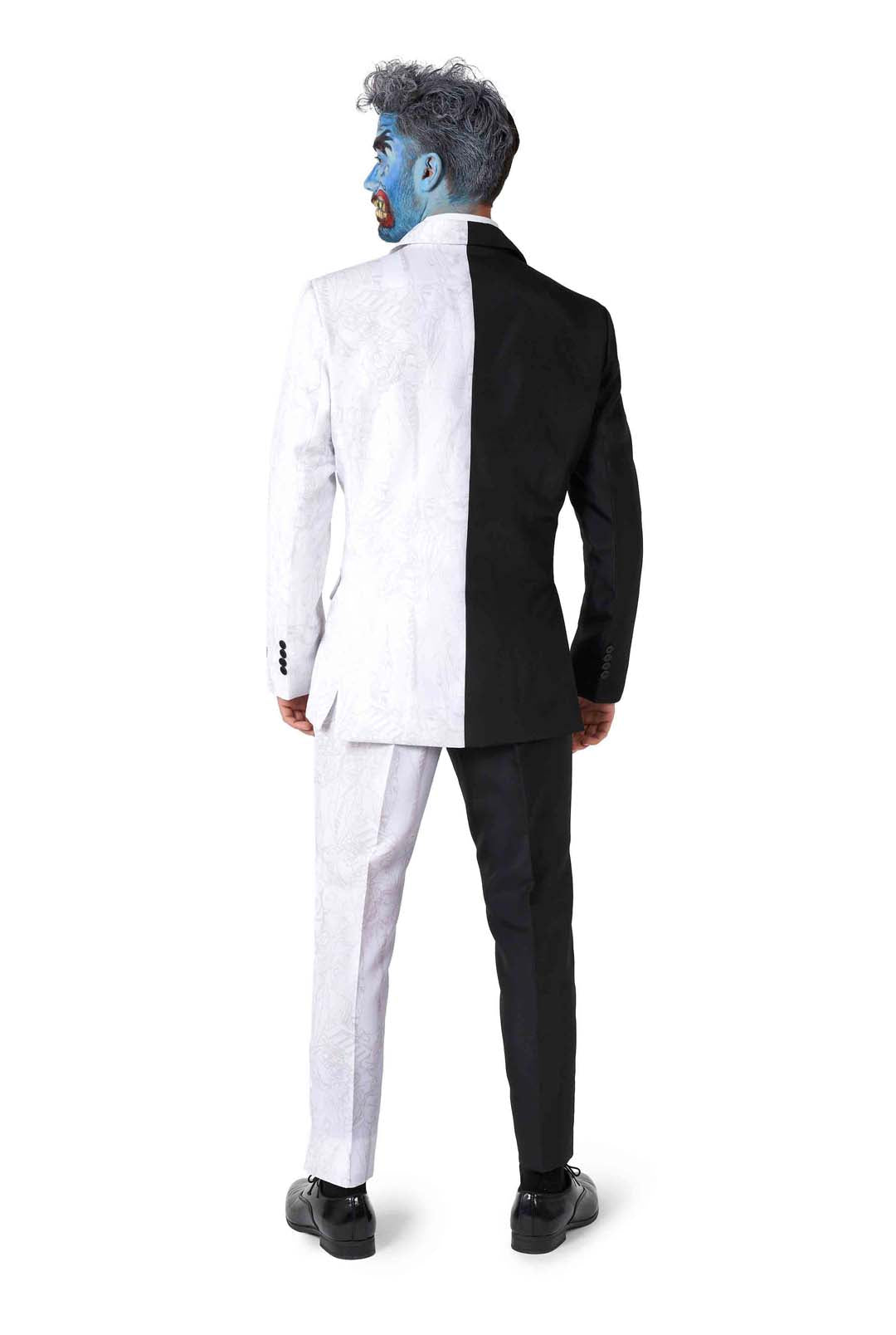 A person stands with their back to the camera, dressed in the Two Face costume by Suitmeister. Their face is painted blue on one side and natural on the other, perfectly mirroring the half-white, half-black design of their suit.