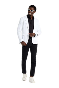 A man dressed in a Suitmeister Sequins Blazer White, paired with a black shirt and black pants, stands confidently. He's also sporting white sunglasses and white sneakers, smiling against a plain white backdrop.